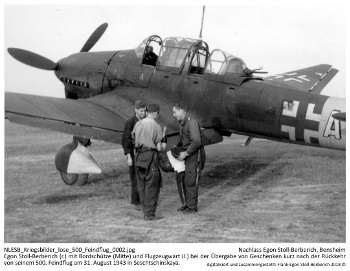 Egon Stoll-Berberich (r.) mit Bordschütze Feldwebel Heinz Ley (Mitte) und Flugzeugwart Unteroffizier Heikstein (l.) bei der Übergabe von Geschenken kurz nach der Rückkehr von seinem 500. Feindflug am 31. August 1943 in Seschtschinskaya. NLESB_Kriegsbilder_lose_500_Feindflug_0002.