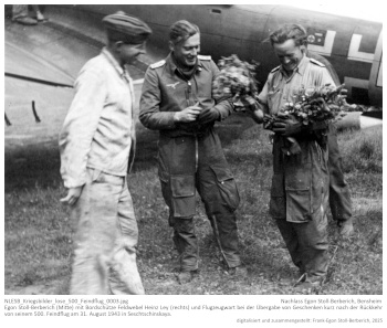 Egon Stoll-Berberich (Mitte) mit Bordschütze Feldwebel Heinz Ley (rechts) und Flugzeugwart bei der Übergabe von Geschenken kurz nach der Rückkehr von seinem 500. Feindflug am 31. August 1943 in Seschtschinskaya. NLESB_Kriegsbilder_lose_500_Feindflug_0003.