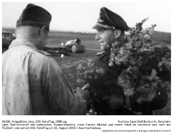 Egon Stoll-Berberich mit Kameraden, Blumensträußen, einer Flasche Alkohol und einem Pokal als Geschenk kurz nach der Rückkehr von seinem 500. Feindflug am 31. August 1943 in Seschtschinskaya. NLESB_Kriegsbilder_lose_500_Feindflug_0006.