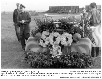 Egon Stoll-Berberichs "Bombe": mit Blumen und Stuka-Modell geschmücktes Fahrzeug zu Egon Stoll-Berberichs 500. Feindflug am 31. August 1943 in Seschtschinskaya; Egon Stoll-Berberich 2. von links. NLESB_Kriegsbilder_lose_500_Feindflug_0012.