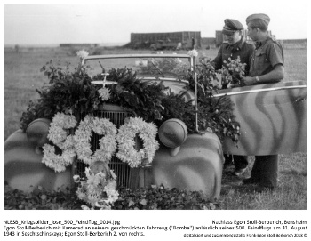 Egon Stoll-Berberich mit Kamerad an seinem geschmückten Fahrzeug ("Bombe") anlässlich seines 500. Feindflugs am 31. August 1943 in Seschtschinskaya; Egon Stoll-Berberich 2. von rechts. NLESB_Kriegsbilder_lose_500_Feindflug_0014.