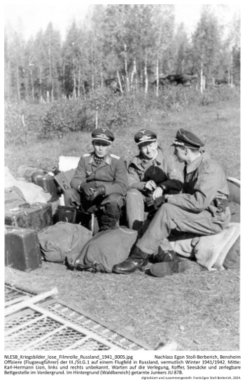 Offiziere (Flugzeugführer) der III./St.G.1 auf einem Flugfeld in Russland, vermutlich Winter 1941/1942. Mitte: Karl-Hermann Lion, links und rechts unbekannt. Warten auf die Verlegung, Koffer, Seesäcke und zerlegbare Bettgestelle im Vordergrund. Im Hintergrund (Waldbereich) getarnte Junkers JU 87B. NLESB_Kriegsbilder_lose_Filmrolle_Russland_1941_0005